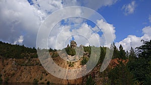 An abandoned stone quarry filled with water and trees around.