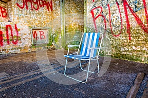 abandoned summer chair inside of an empty room decorated by various graphitti in gibraltar...IMAGE photo