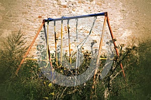 Abandoned swing in thistles in scary, grungy image