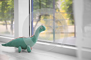 Abandoned toy dinosaur on window sill