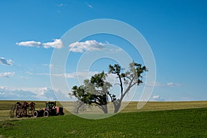 Abandoned tractor and farming equipment in an open field near a large tree in The Palouse region of Eastern Washington State