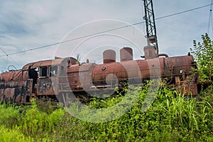 Abandoned train. Abandoned railway. Old rusty steam locomotive overgrown by plants