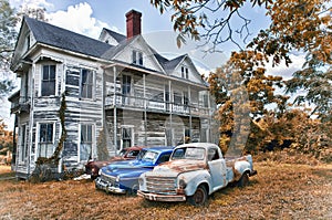 Abandoned Two Story Farmhouse with Three Vintage Automobiles photo