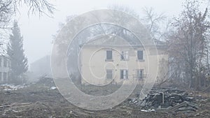 An abandoned two-story wooden house by the road on a foggy day