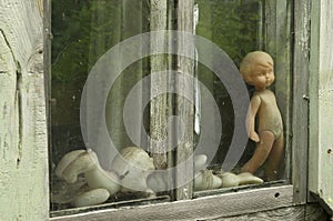 Abandoned unbranded soviet toys behind the glass of an uninhabited house