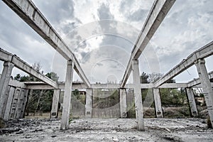 Abandoned unfinished concrete roofless hangar in cloudy day