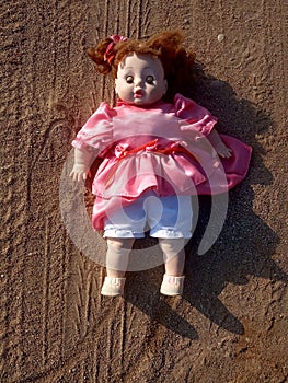 Abandoned unnecessary doll in a beautiful pink dress