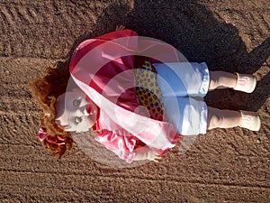 Abandoned unnecessary doll in a beautiful pink dress