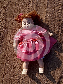 Abandoned unnecessary doll in a beautiful pink dress