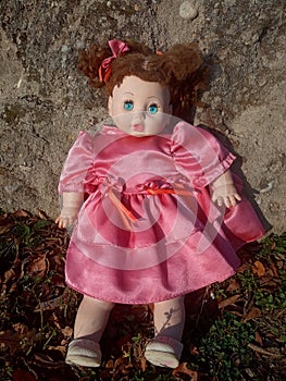 Abandoned unnecessary doll in a beautiful pink dress