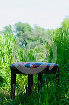 Abandoned upholstered chair in tall grass