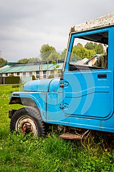 Abandoned vintage car blue lush green grass in college campus