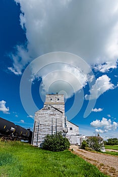 An abandoned vintage grain elevator in Battrum, Saskatchewan with a train beside it