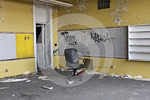 Abandoned vintage yellow classroom with office chair