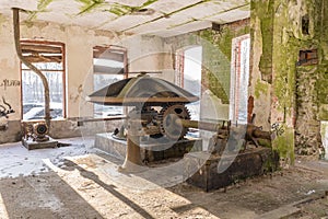 Abandoned water mill. Rusty wheels and green moss covered the old brick wall