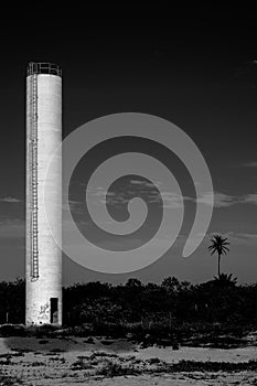 Abandoned water tower with palm tree in backgroung