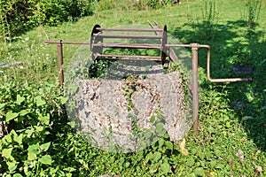 Abandoned well in a field overgrown with green ivy