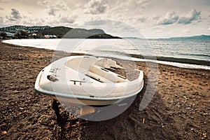 Abandoned white fiberglass motorboat ashore on the beach