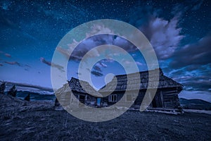 Abandoned wooden houses on a hill under the night starry sky