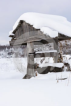 Abandoned wooden village well in deep snow