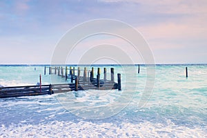 Abandoned wooden wharf in sea within sunrise.Gentle blue pink color of sky, blur waves