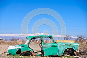 Abandoned wreck of an old green Soviet Russian car in the middle of dry agricultural land in Southern Armenia