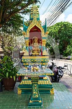 Abandoned yellow-green house of the spirit. House spirit style Thailand on the street under the trees.