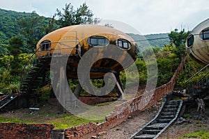 Abandoned yellow rusty UFO house near a forest in Wanli UFO Village, Taiwan photo