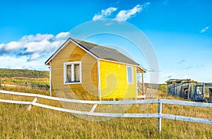 Abandoned yellow small house with white fence in countryside