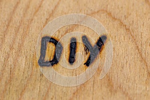An abbreviation DIY - do it yourself - burned by hand with electrical woodburner on plywood surface