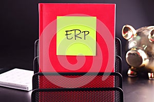 Abbreviation ERP - Enterprise Resource Planning on a yellow sticker glued to a red notebook