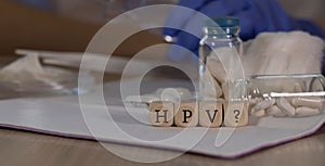 Abbreviation HPV with question mark for human papilloma virus infection composed of wooden dices. Pills, documents and a pen in