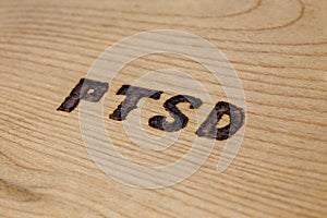 An abbreviation PTSD - post traumatic stress disorder - burned by hand on flat wooden board in diagonal composition
