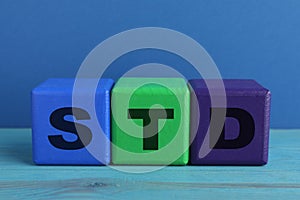 Abbreviation STD made with cubes on light blue wooden table