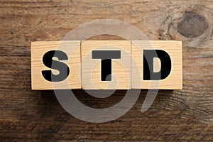 Abbreviation STD made with cubes on wooden table, flat lay