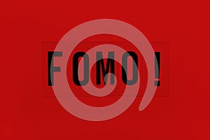 Abbreviation word FOMO on transparent plastic on red background. It means Fear Of Missing Out, non-stop internet surfing. Concept