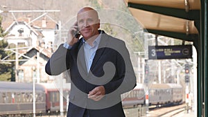 Businessman Waiting and Talking to Mobile Phone in a Train Station