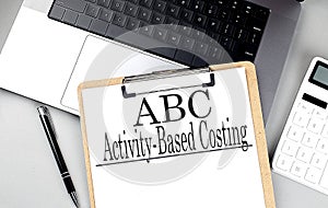 ABC -ACTIVITY-BASED COSTING word on clipboard on laptop with calculator and pen photo