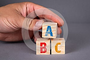 ABC alphabet wooden blocks and a man& x27;s hand on a gray background