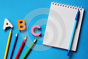 ABC-the first letters of the English alphabet on a blue background. Notebook and pen. Empty space for text. Learn foreign