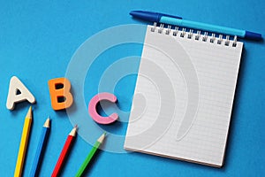 ABC-the first letters of the English alphabet on a blue background. Notebook and pen. Empty space for text. Learn foreign