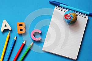 ABC-the first letters of the English alphabet on a blue background. Notebook and pen. Empty space for text. Learn foreign
