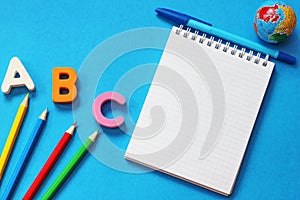 ABC-the first letters of the English alphabet on a blue background. Notebook and pen. Empty space for text. Learn foreign