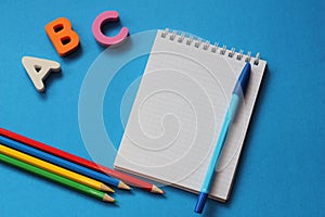 ABC-the first letters of the English alphabet on a blue background. Notebook and pen. Empty space for text. Learn foreign