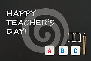 Abc letters and chipboard miniature on blackboard with text happy teacher`s day