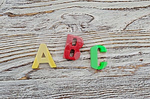 ABC spelling of colorful plastic letters on wooden background