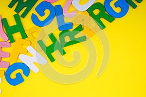 ABC wooden letters alphabet scattered on a yellow background