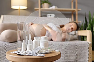 Abdomen parenthood pain. Ache pregnant maternity. Big variety of pills on table with sick pregnant woman lying on sofa at home on