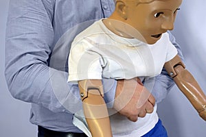 Abdominal thrusts the Heimlich maneuver or Heimlich manoeuvre on a simulation mannequin child dummy during medical training