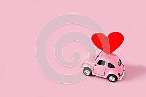 Abinsk, 12 14 2019: Pink retro toy car lucky red heart on pink background. March 8, International Happy Women`s Day photo